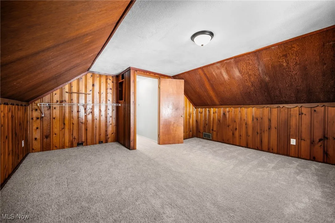 Bedroom featuring wood walls, lofted ceiling, and carpet flooring