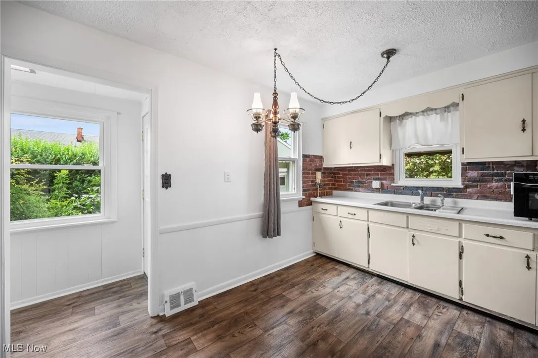Kitchen featuring wood-style flooring, light countertops, a chandelier, healthy amount of natural light, and a textured ceiling