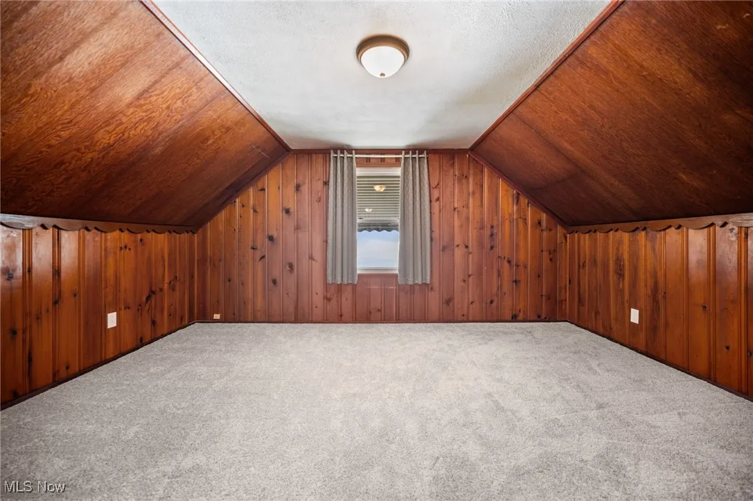 Bedroom featuring carpet floors, lofted ceiling, and wood walls