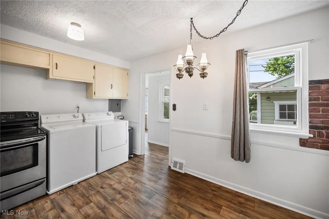 Kitchen featuring a textured ceiling, a chandelier, wood-style flooring, and washing machine and dryer