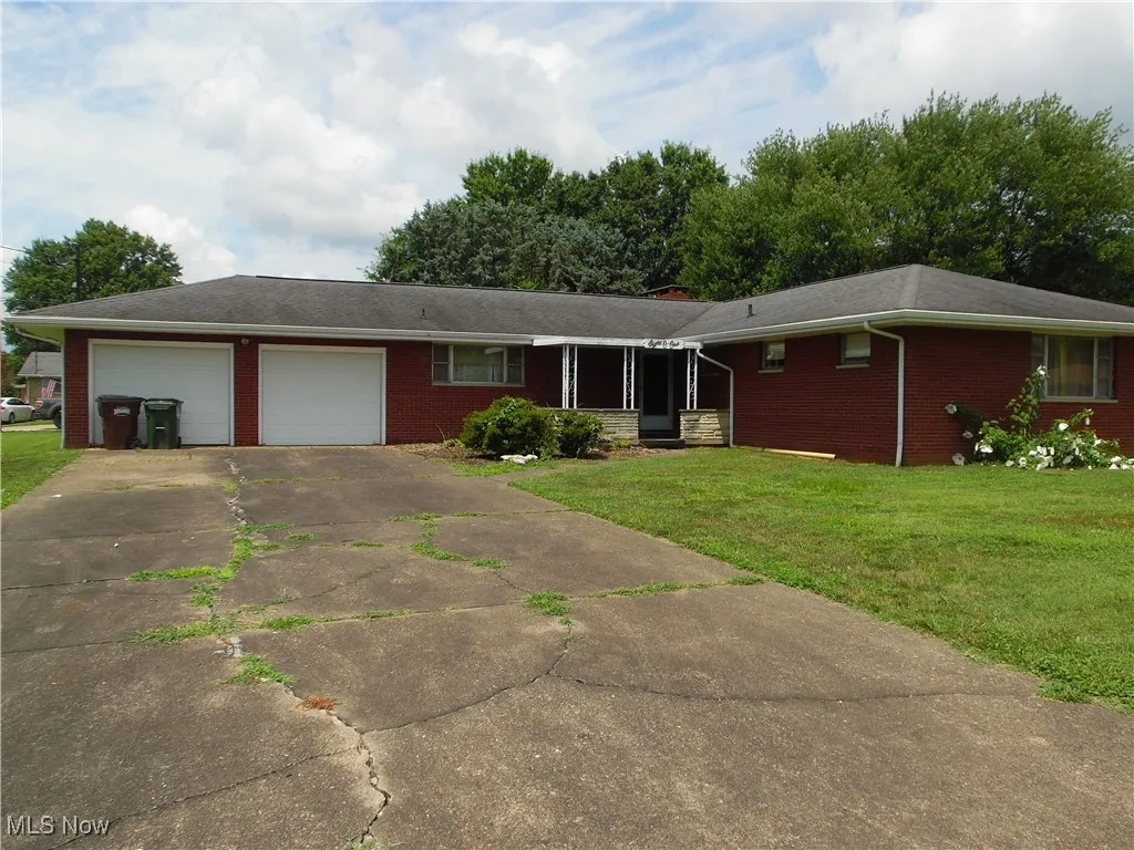 Ranch-style house featuring an attached garage, brick siding, driveway, and a front yard