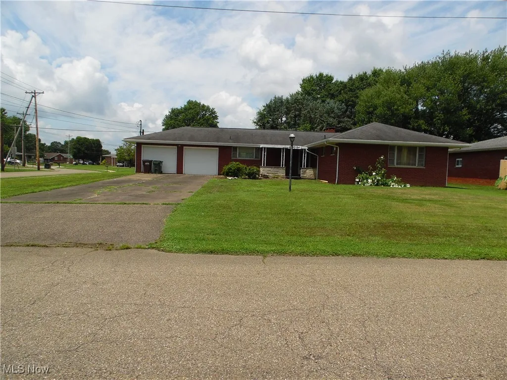 Ranch-style home with a garage, brick siding, concrete driveway, a front lawn, and a chimney