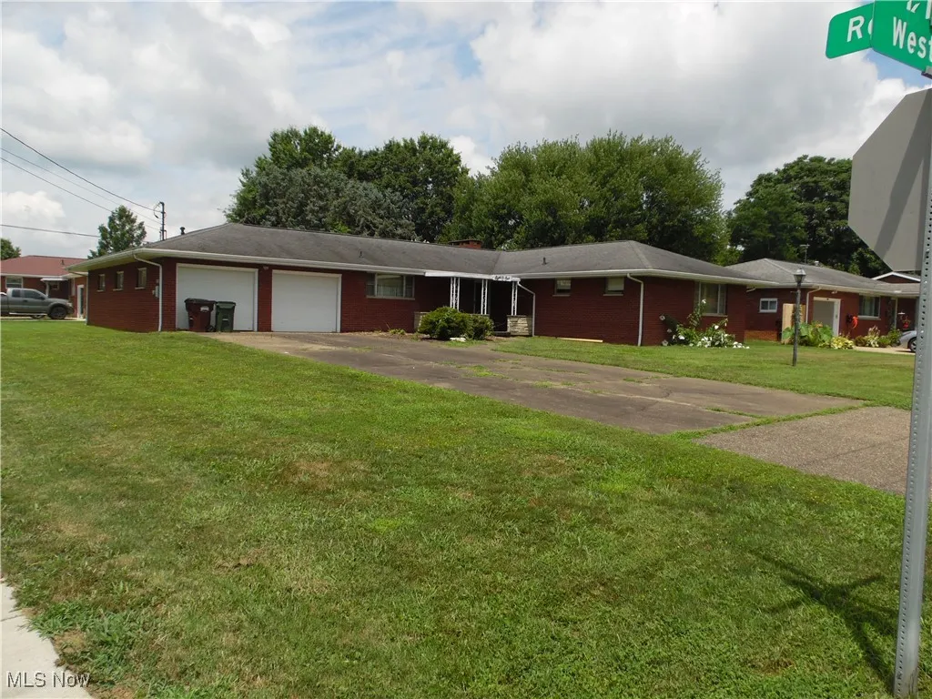 Single story home with a garage, brick siding, driveway, and a front yard