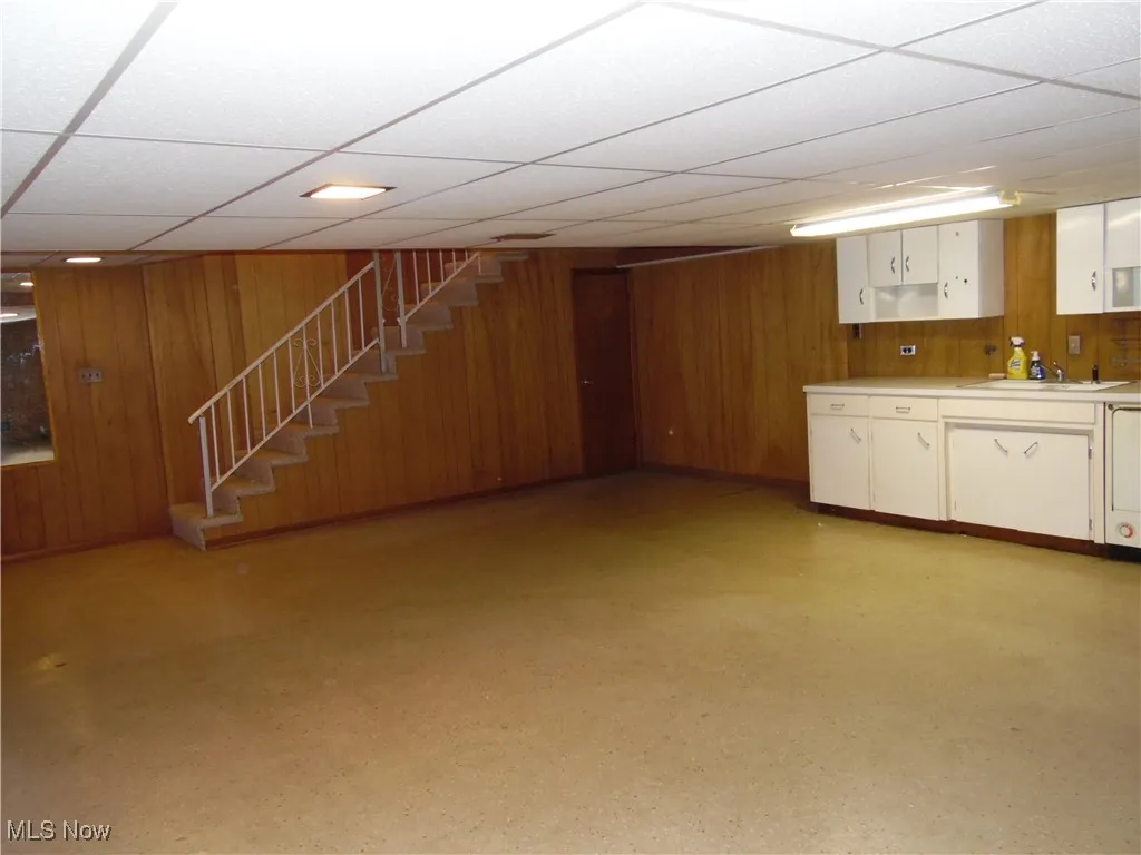 Finished below grade area with wooden walls, stairs, and a paneled ceiling