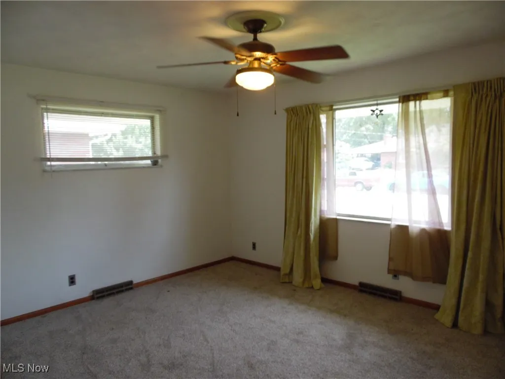 Empty room featuring a ceiling fan and carpet floors