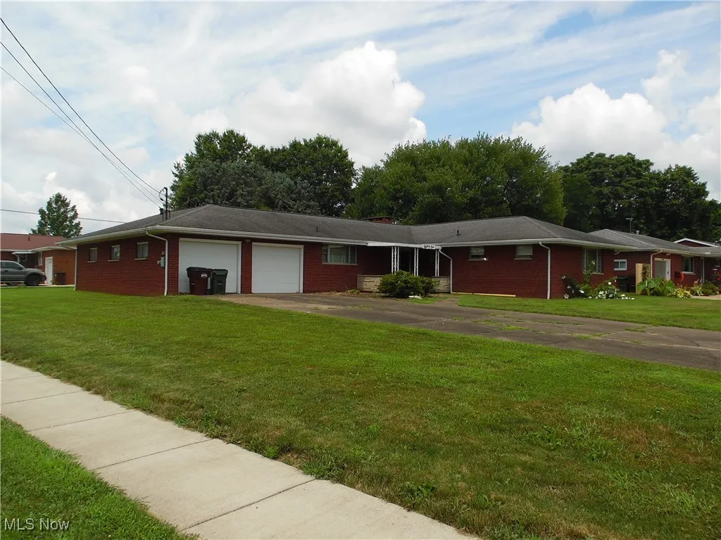 Ranch-style home featuring an attached garage, driveway, a front lawn, and brick siding
