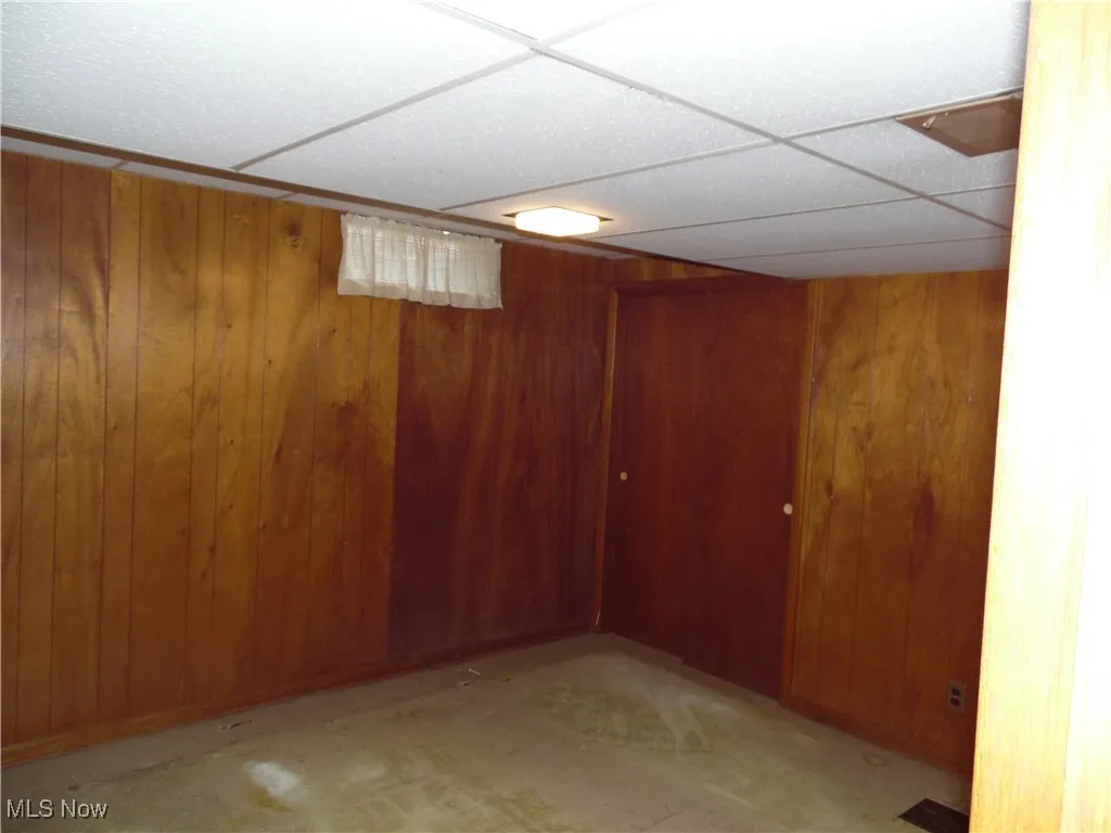 Finished basement featuring wood walls and a drop ceiling