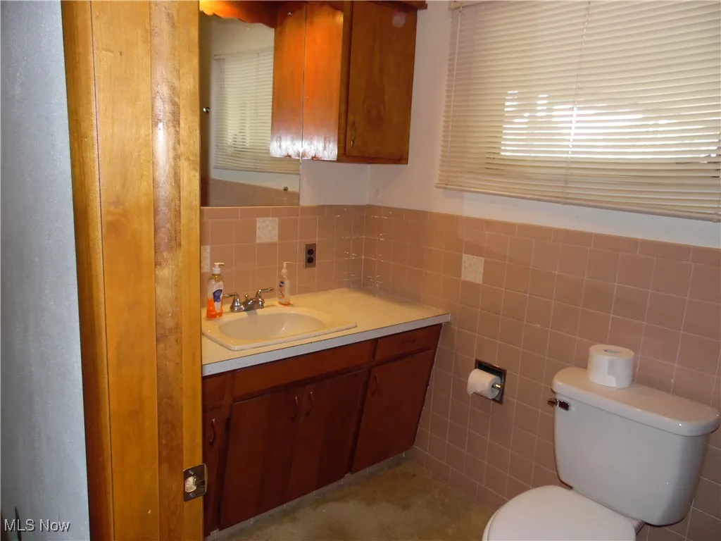 Bathroom featuring vanity, tile walls, and a wainscoted wall