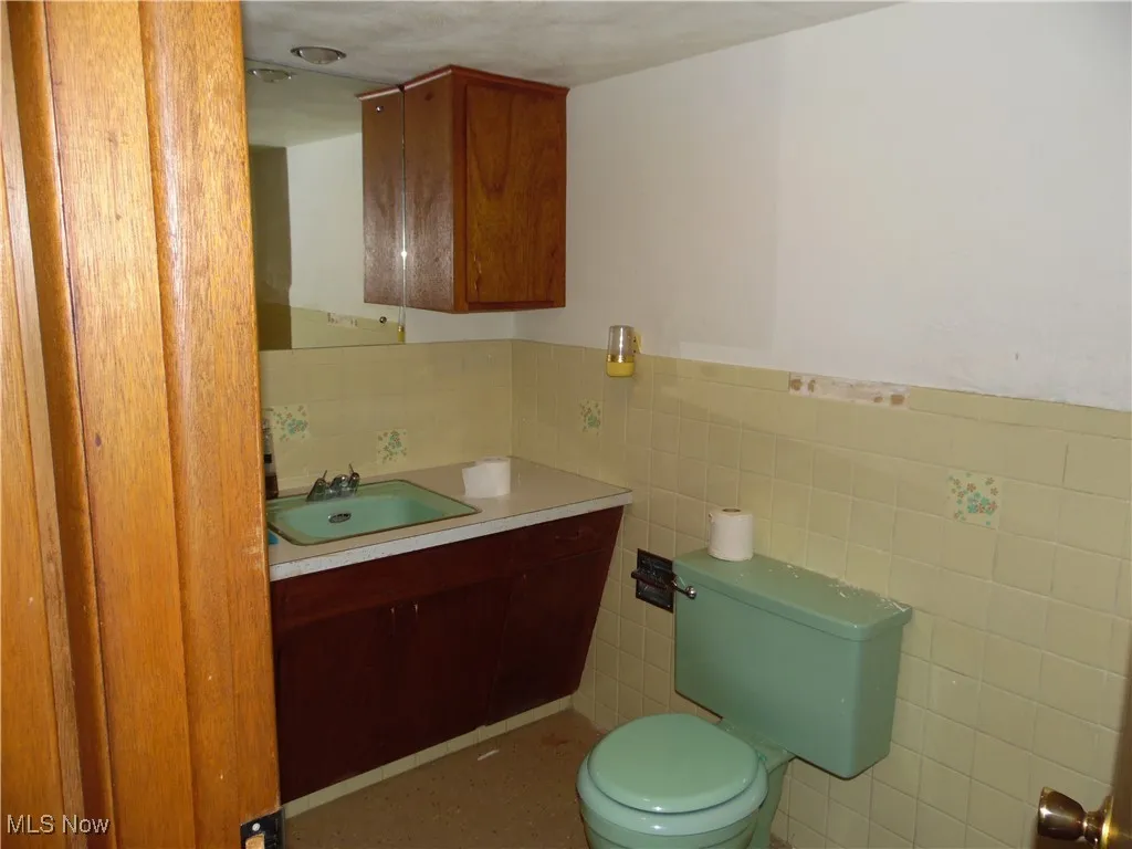 Half bathroom with vanity, tile walls, and wainscoting