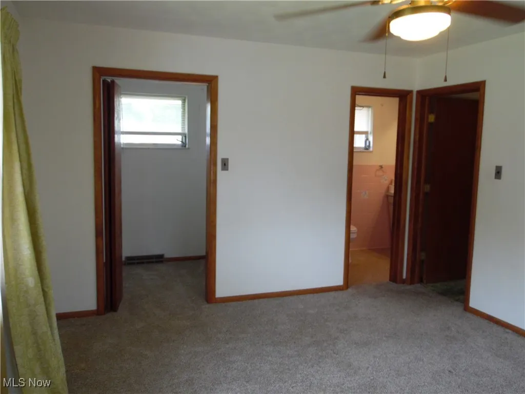 Carpeted spare room with ceiling fan and baseboards