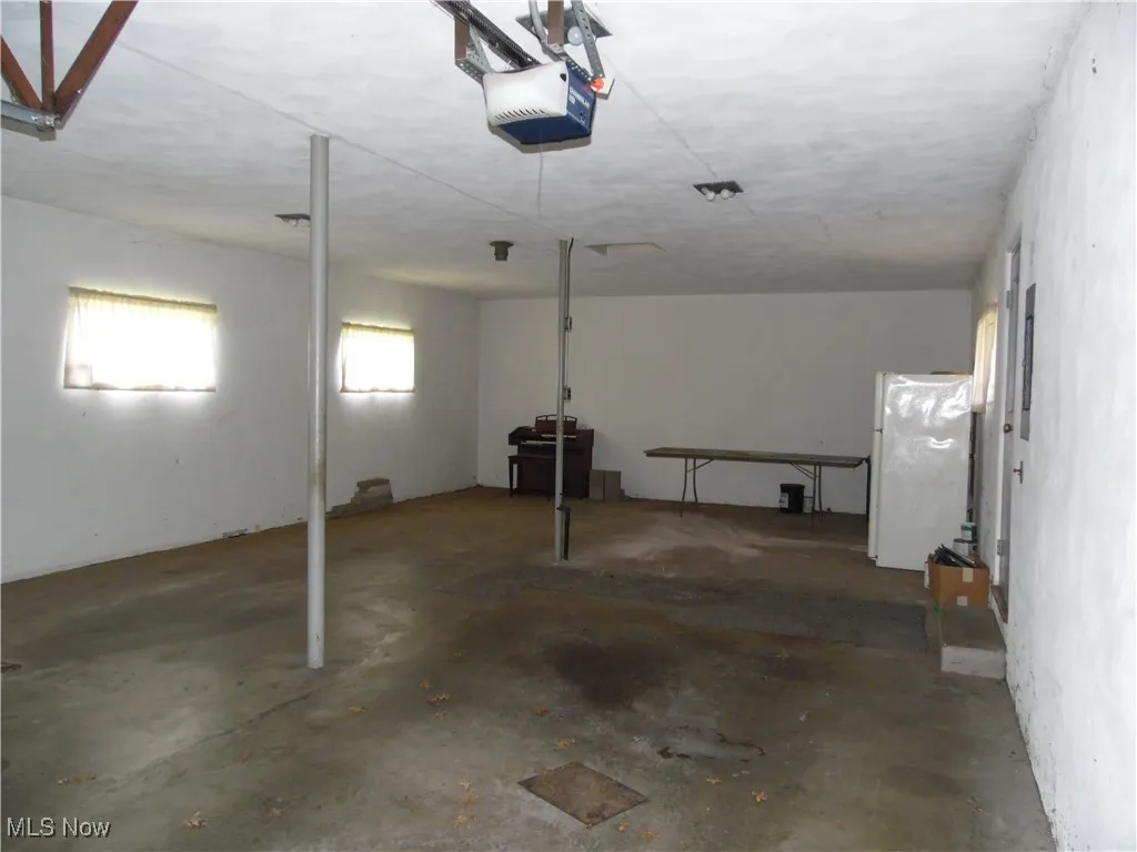 Garage with freestanding refrigerator and a garage door opener