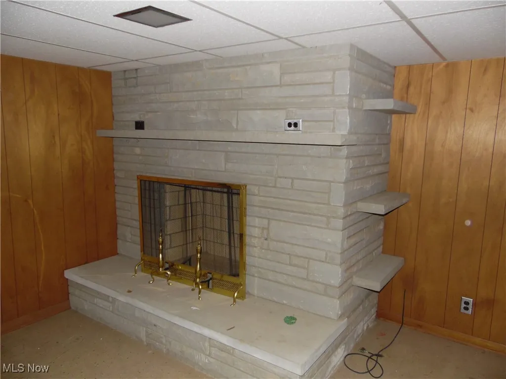 Detailed view of wooden walls, a large fireplace, and a drop ceiling