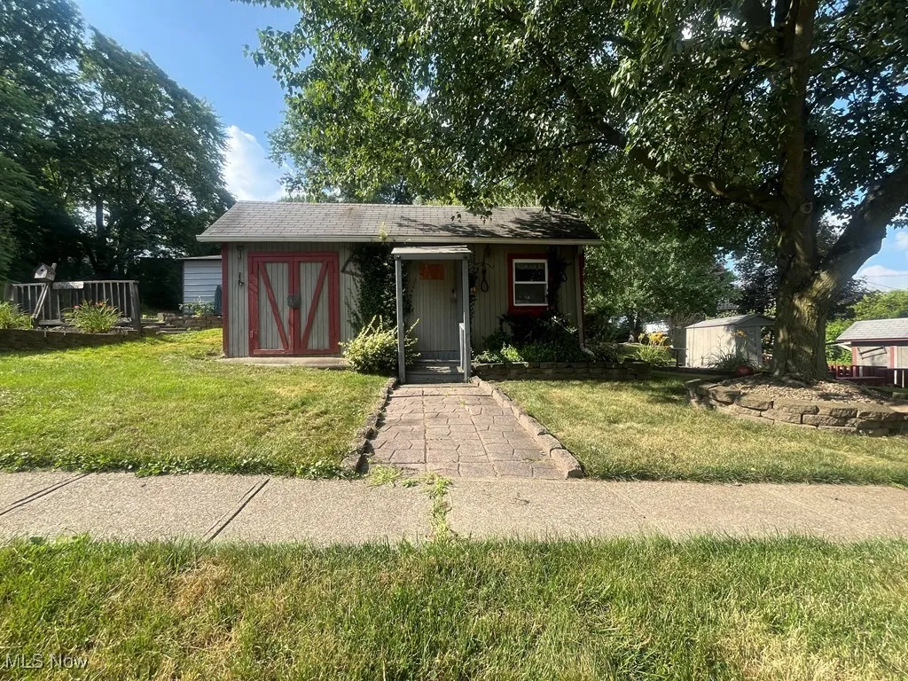 View of front facade with a front lawn and a storage shed