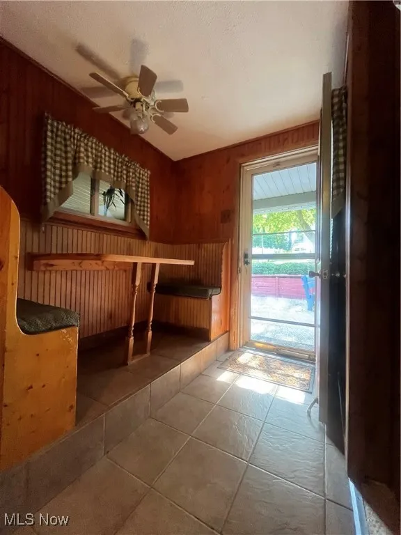 Unfurnished bedroom featuring access to exterior, wooden walls, and tile patterned flooring
