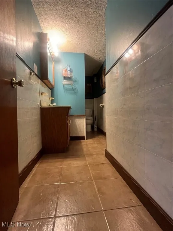 Hallway with a textured ceiling and tile patterned flooring