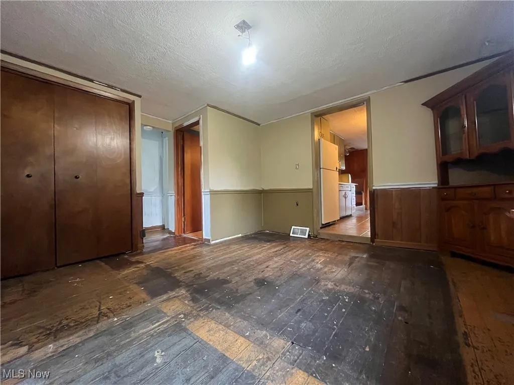 Unfurnished living room with wainscoting and a textured ceiling