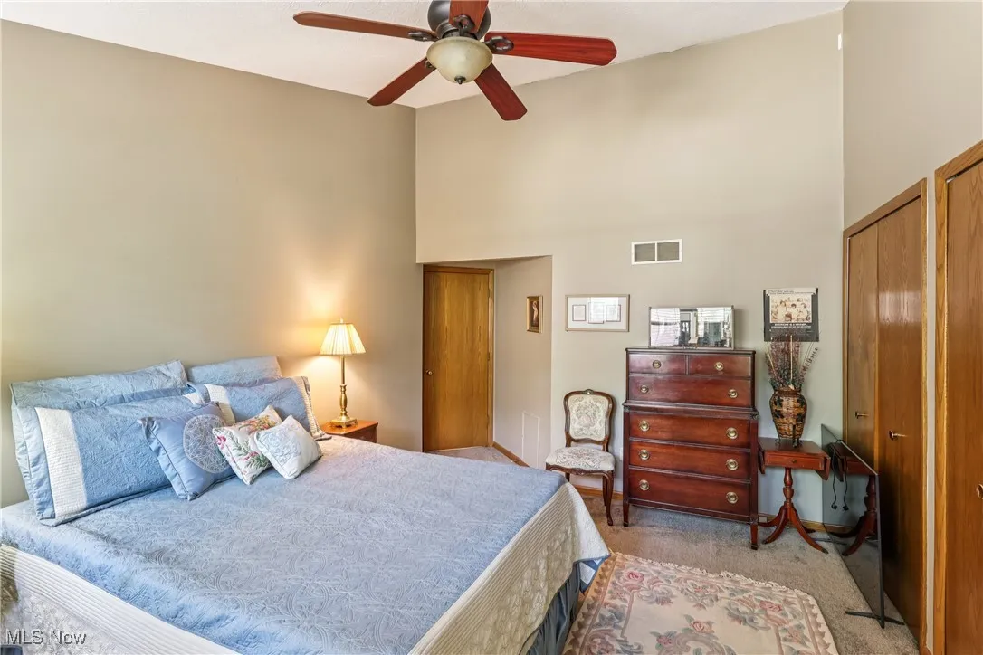 Bedroom featuring vaulted ceiling, ceiling fan / light, double closets, and carpet flooring