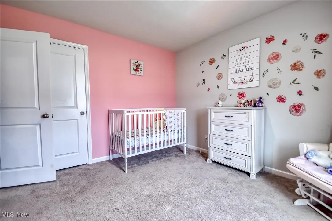 Carpeted bedroom featuring a crib and baseboards