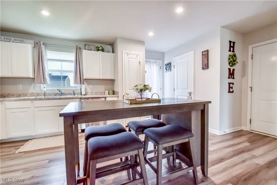 Kitchen featuring light wood-style floors, white cabinetry, a kitchen breakfast bar, recessed lighting, and stainless steel dishwasher