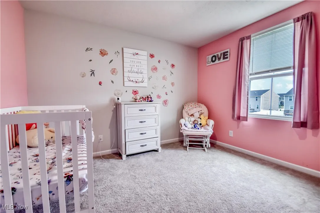 Carpeted bedroom with a crib and baseboards