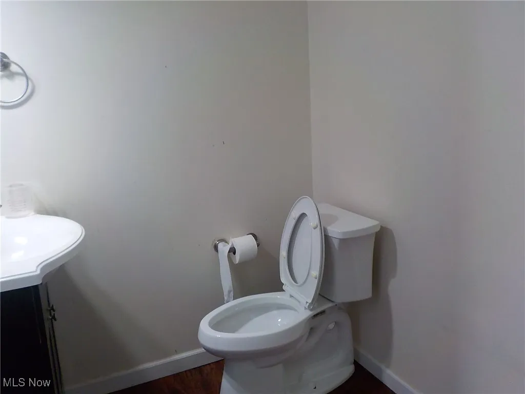 Half bathroom with baseboards and wood finished floors