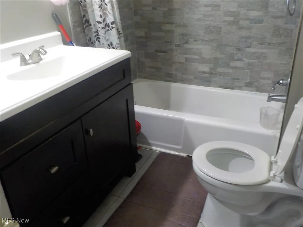 Bathroom featuring tile patterned floors, shower / tub combo with curtain, and vanity