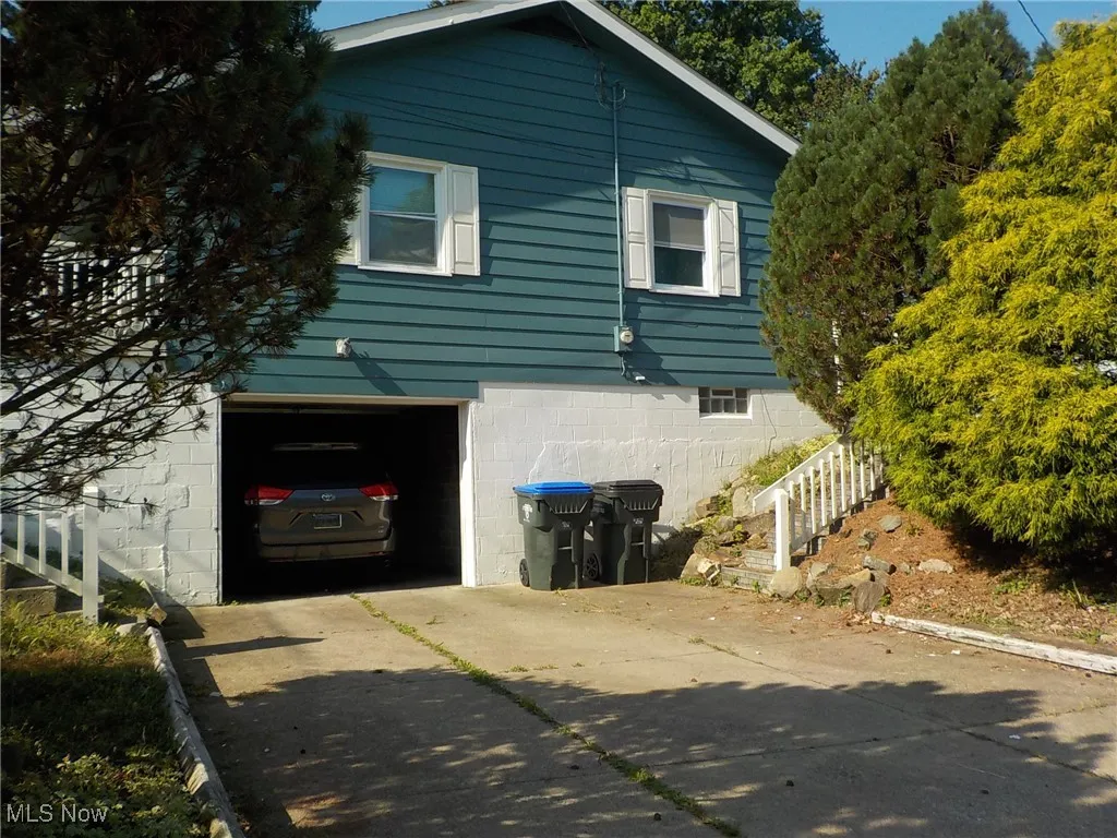 View of property exterior featuring concrete driveway and an attached garage
