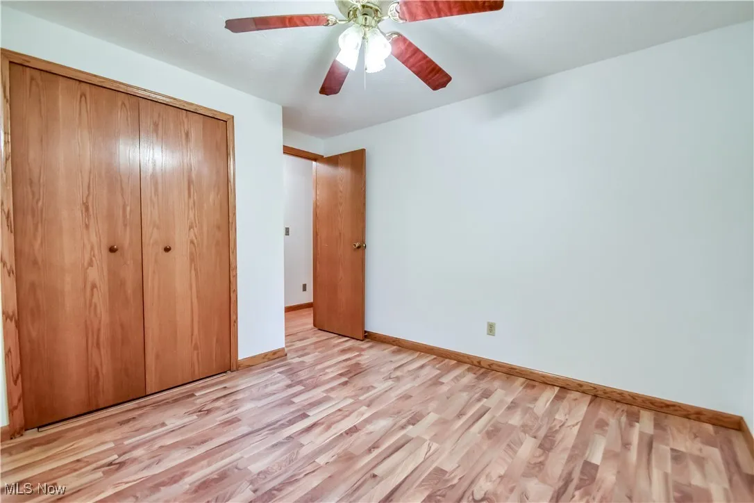 Unfurnished bedroom with light wood-style floors, a closet, and ceiling fan