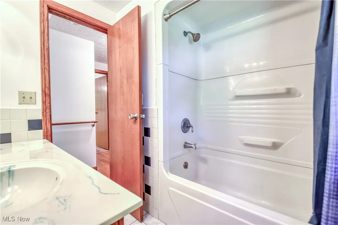 Full bath with shower / bath combo with shower curtain, vanity, and a textured ceiling