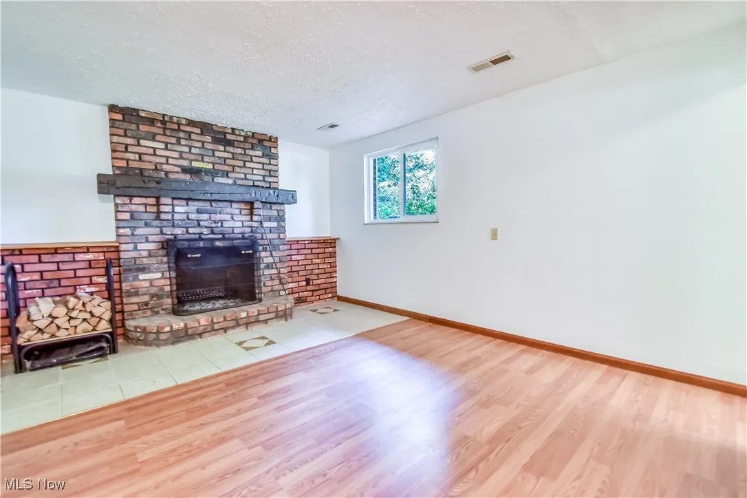 Living area with wood finished floors, a fireplace, and a textured ceiling
