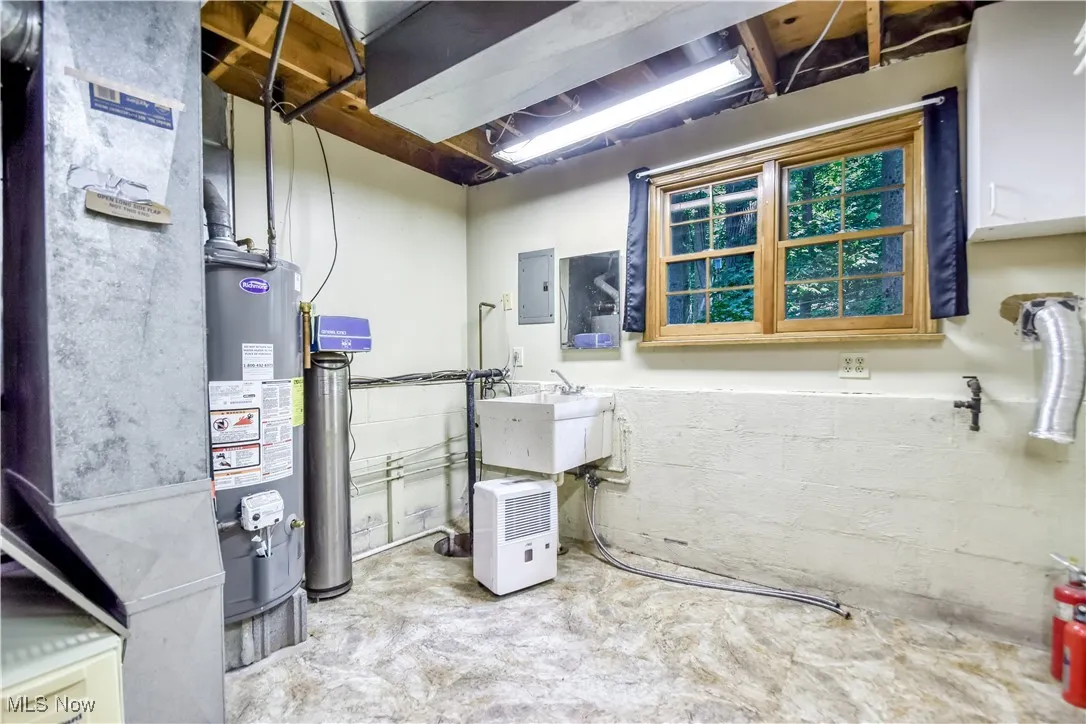 Utility room with heating unit, gas water heater, and electric panel