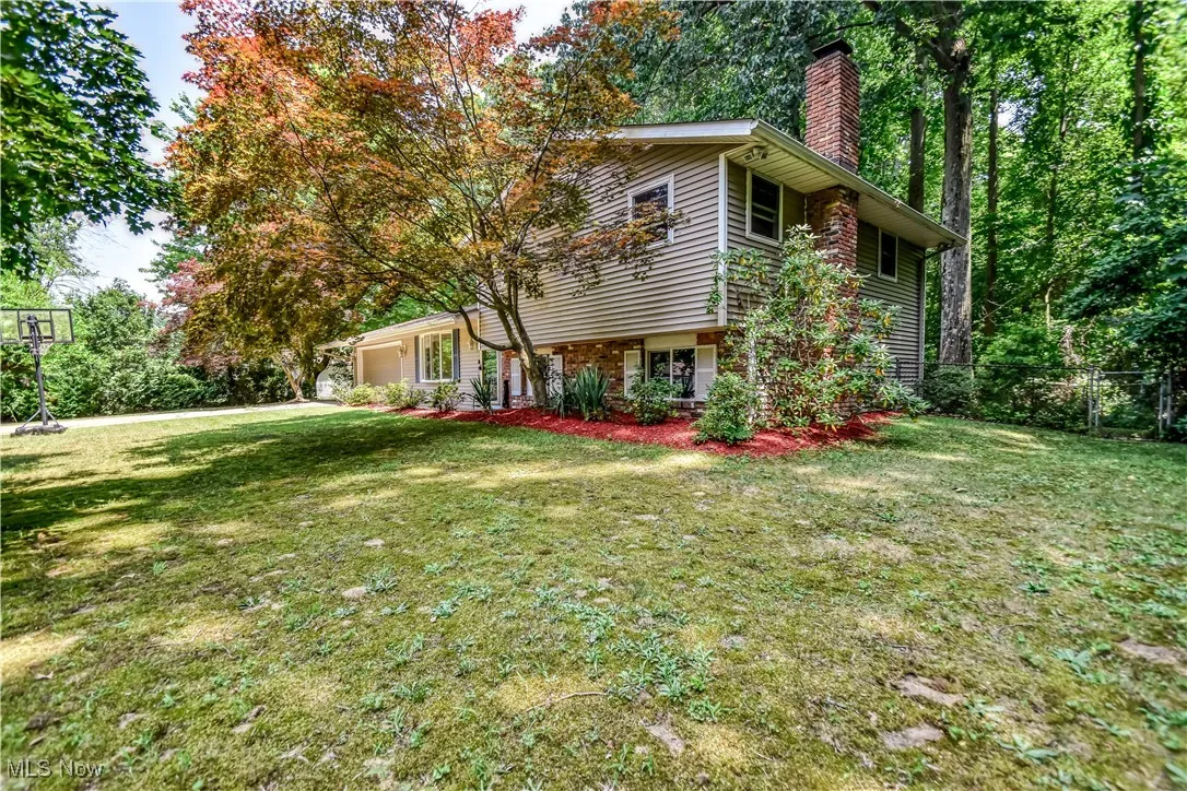 View of property exterior featuring an attached garage, a chimney, and brick siding