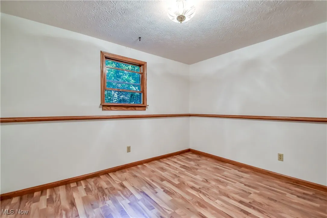 Unfurnished room with wood finished floors and a textured ceiling