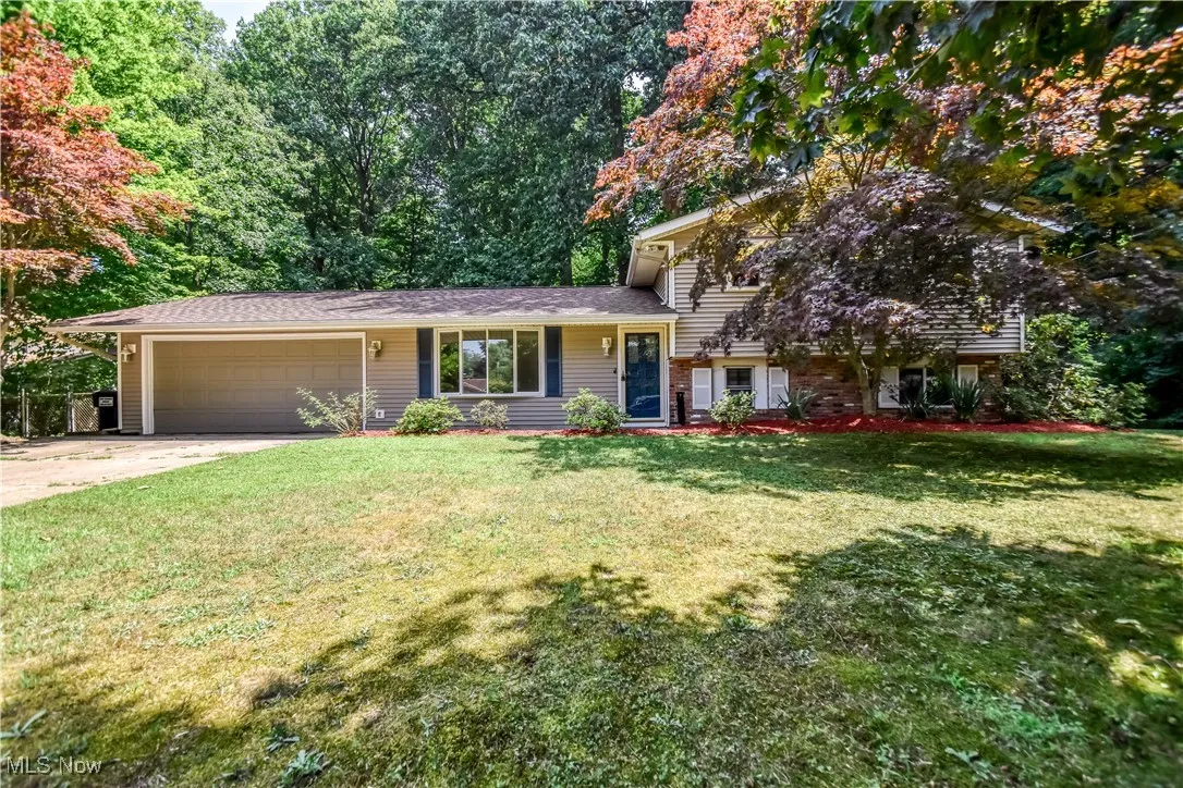 Tri-level home featuring concrete driveway, a garage, and a front yard