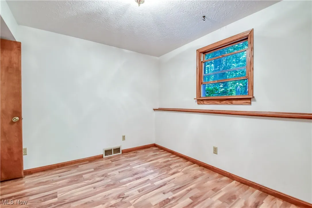 Unfurnished room featuring wood finished floors and a textured ceiling