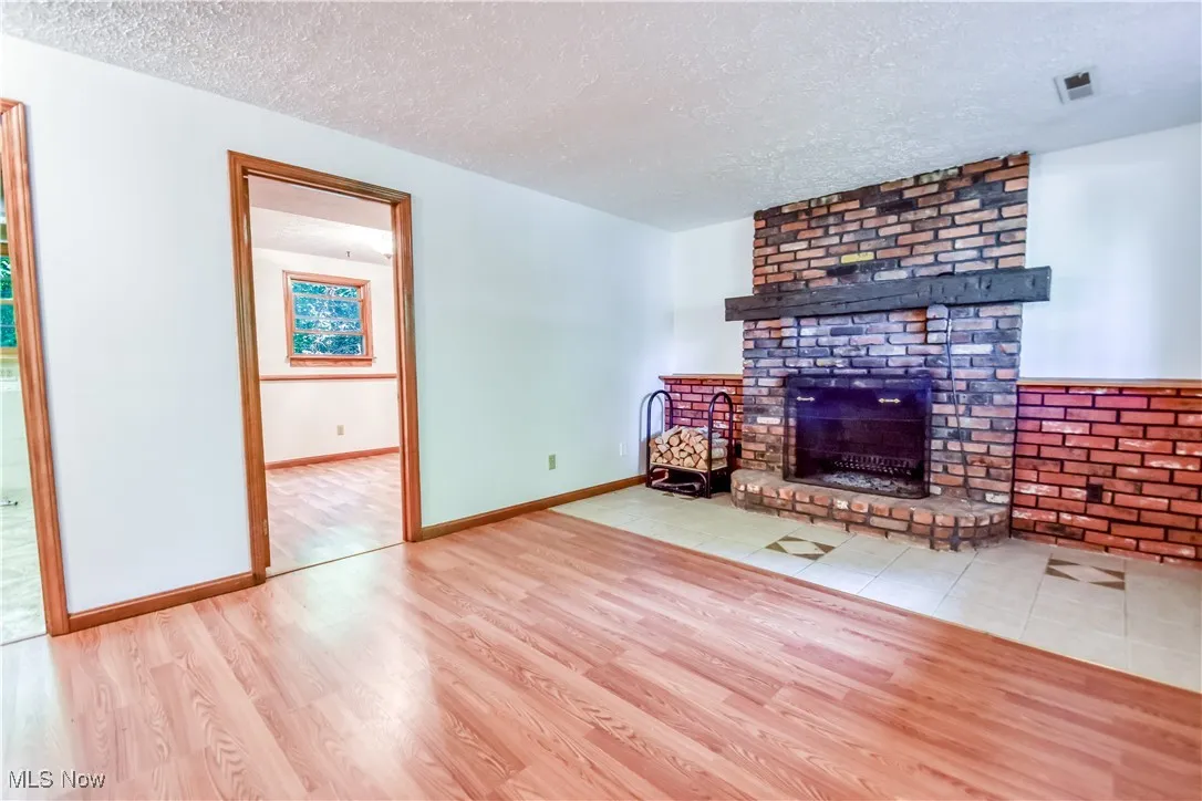 Unfurnished living room with wood finished floors, a textured ceiling, and a fireplace