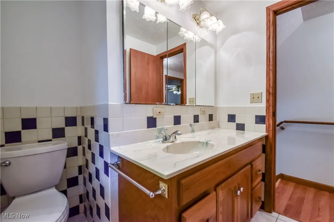 Bathroom featuring vanity, tile walls, a wainscoted wall, and tile patterned flooring