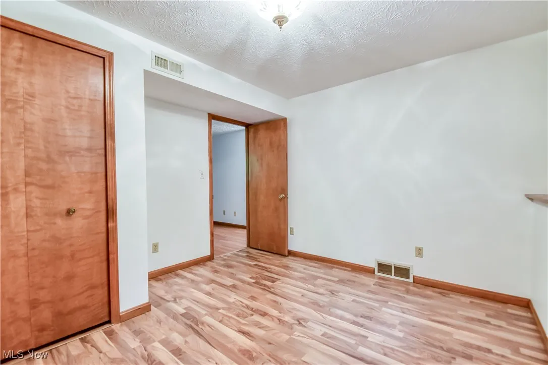 Unfurnished bedroom with light wood-type flooring and a textured ceiling