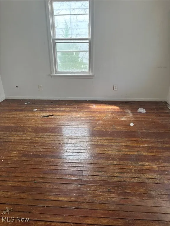 Spare room with hardwood / wood-style floors and baseboards