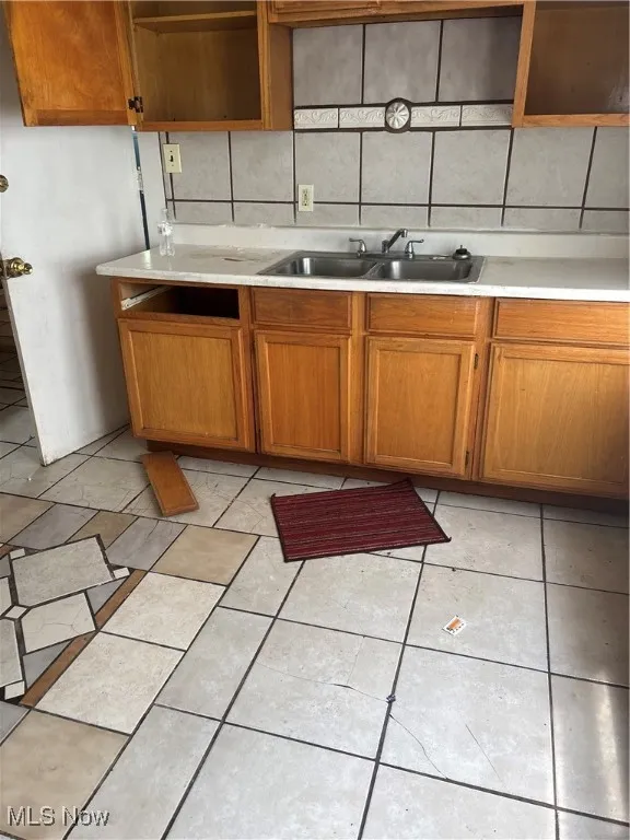 Kitchen with light countertops, brown cabinetry, and open shelves