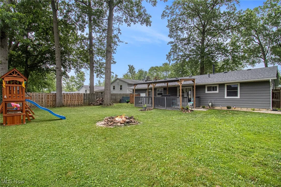 Fenced backyard featuring an outdoor fire pit and a playground