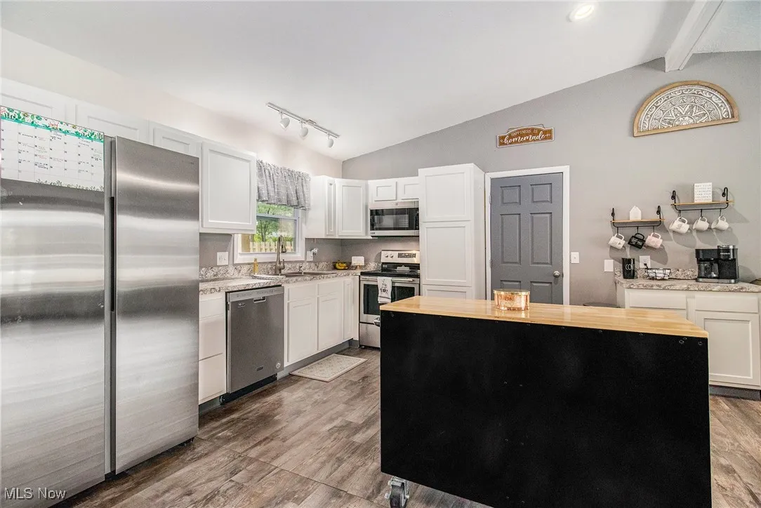 Kitchen featuring stainless steel appliances, wood finished floors, wood counters, and a center island