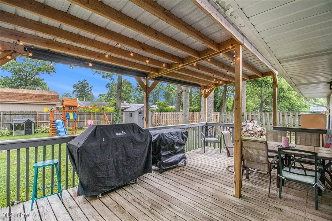 Wooden terrace with a storage shed, area for grilling, a fenced backyard, a playground, and outdoor dining area