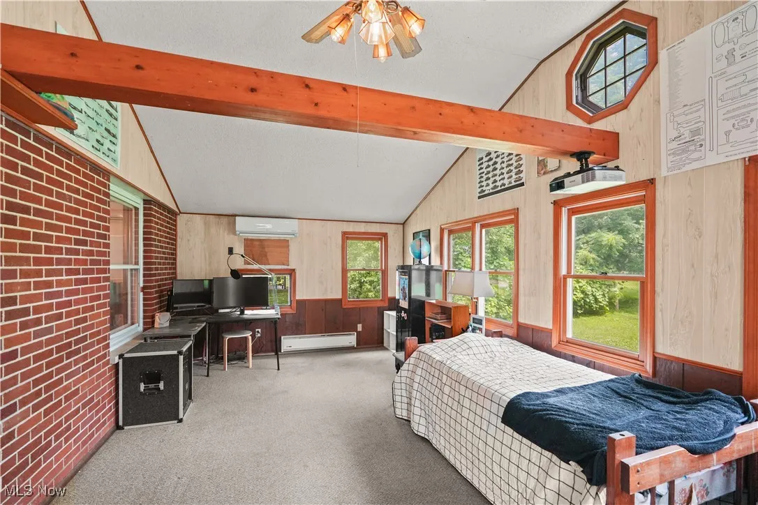 Bedroom featuring wood walls, carpet floors, a baseboard radiator, and a wall unit AC