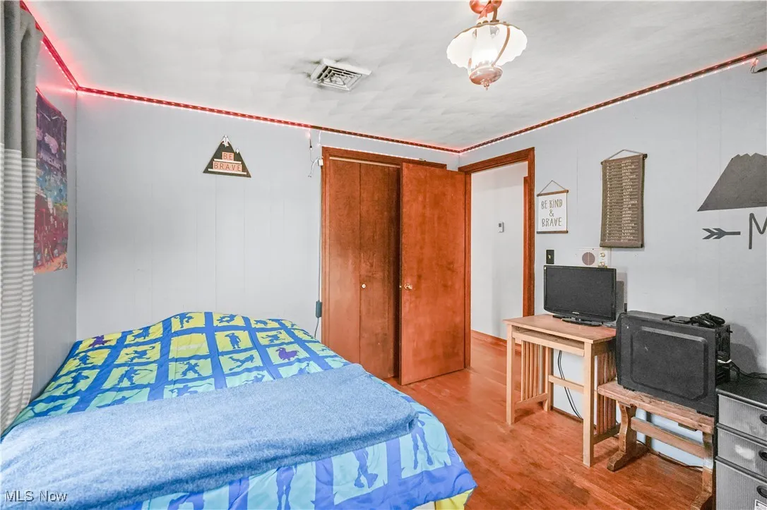Bedroom with wood finished floors and a closet
