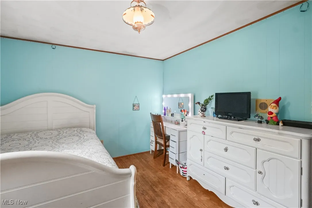 Bedroom featuring wood finished floors and a decorative wall