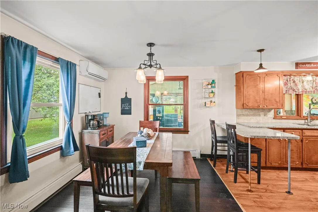 Dining space featuring a chandelier, baseboard heating, light wood-type flooring, and an AC wall unit
