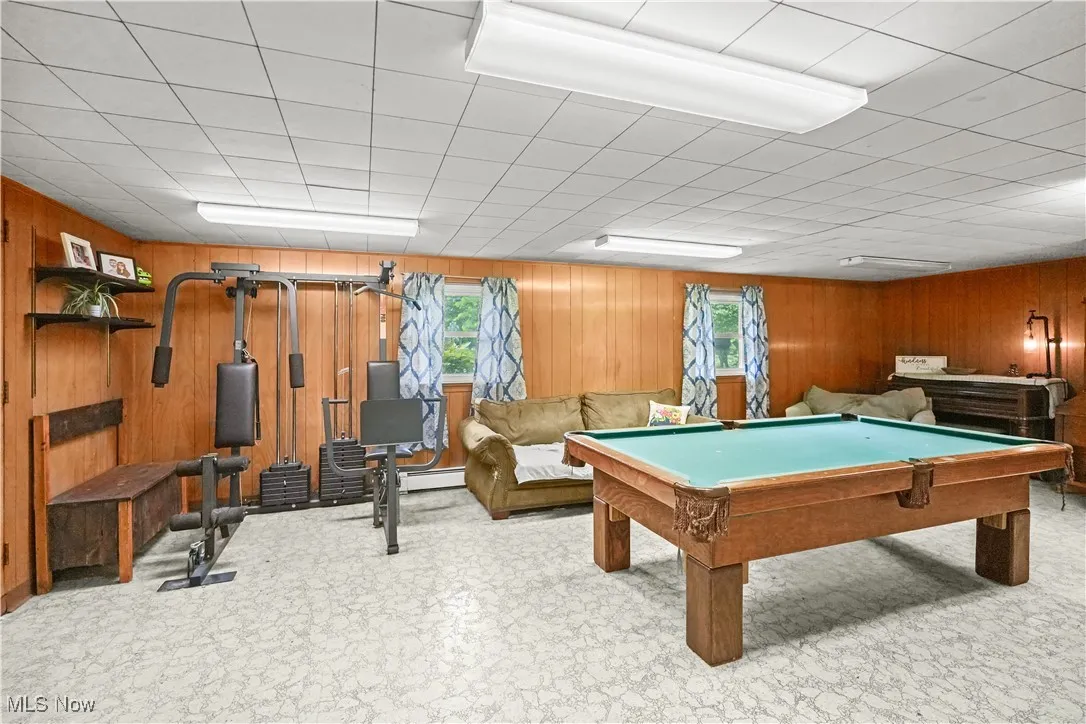 Recreation room with wood walls, tile patterned floors, billiards table, and baseboard heating