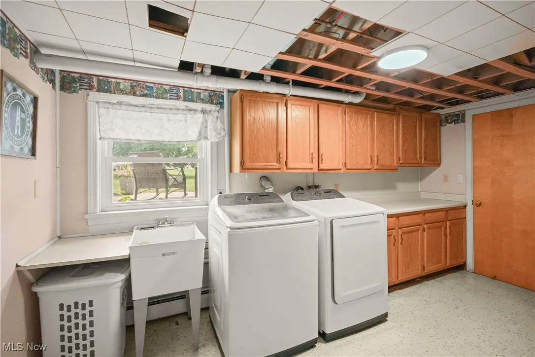 Washroom featuring washer and clothes dryer and cabinet space