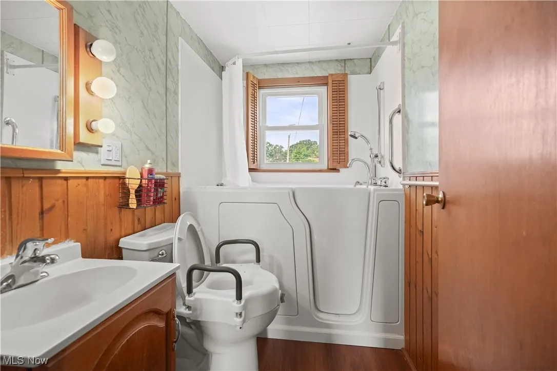 Bathroom featuring wood finished floors, vanity, and wood walls